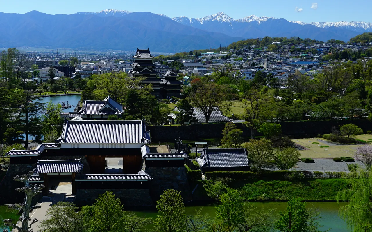 Matsumoto Castle keep with the city and snow-capped Northern Alps behind it