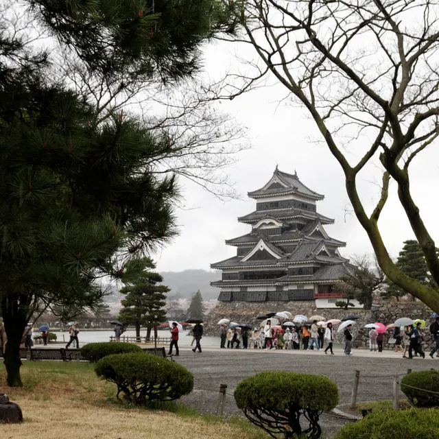 Visitors with umbrellas gathered in front of Matsumoto Castle keep on a busy spring day