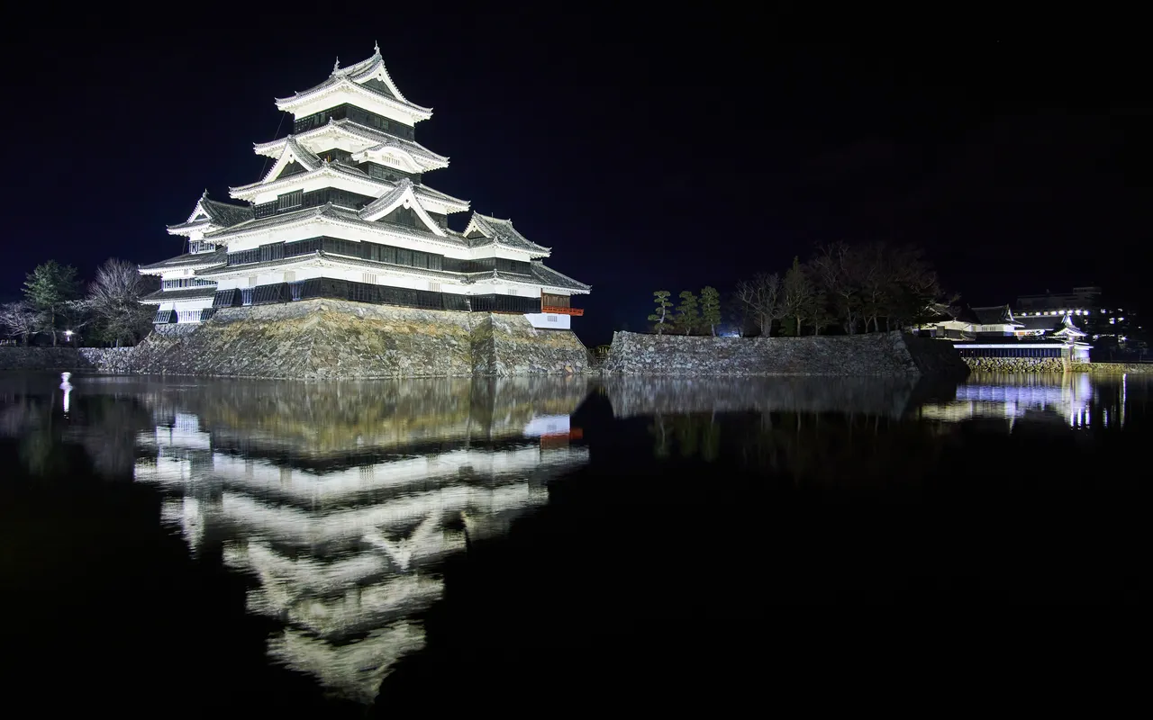 Matsumoto Castle keep lit up at night and reflected in the moat